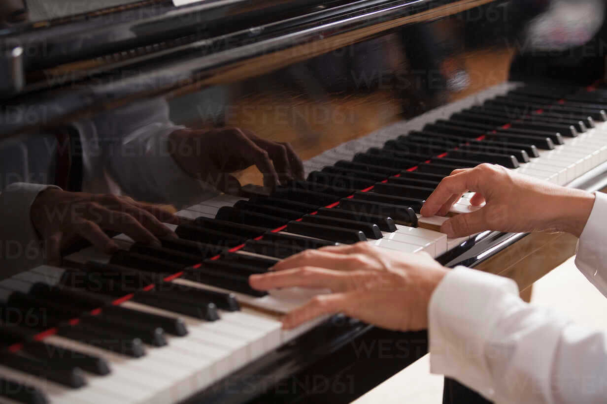 Hands playing a grand piano with passion